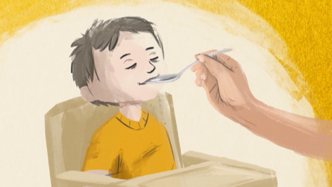 Thumbnail for ALKINDI SPRINKLE administration video for young children that is predominantly yellow in color and designed in a painterly style. Young boy is seen sitting in a high chair being fed from a spoon by a person off camera. He is closing his eyes and wearing a yellow t-shirt.